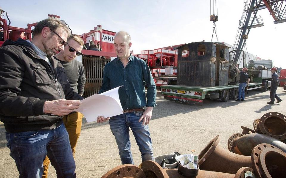 Dirk Dundas (geheel links) bekijkt bij aankomst foto’s en informatie met Tim de Vries (midden) en Hans Altena van de stichting NS 162, terwijl de locomotief van de dieplader wordt gehaald.