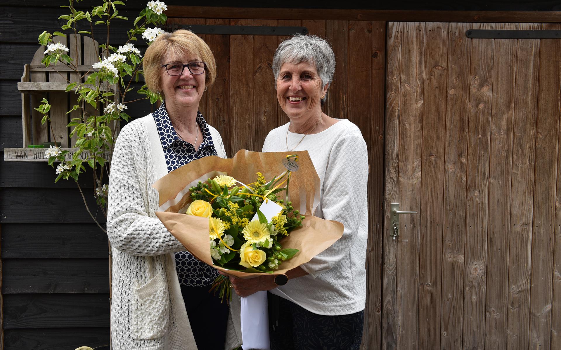 Hannie Spin (links) reikt de bloemen uit aan het nieuwe lid Sien Oosten. Foto Lenus van der Broek