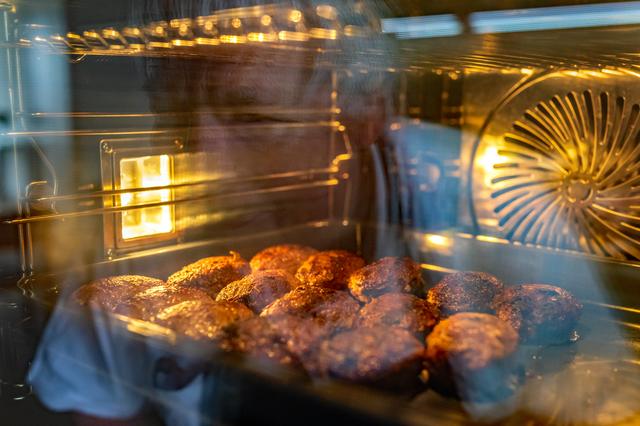 Een oven vol ovale gehaktballen voor verkoop op Koningsdag.