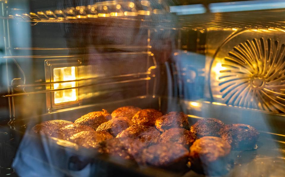 Een oven vol ovale gehaktballen voor verkoop op Koningsdag.