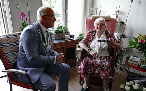 De 100-jarige Jo Stuiver-Conradi uit Joure krijgt burgemeester Fred Veenstra op bezoek. Hij heeft haar geboorteakte meegenomen.